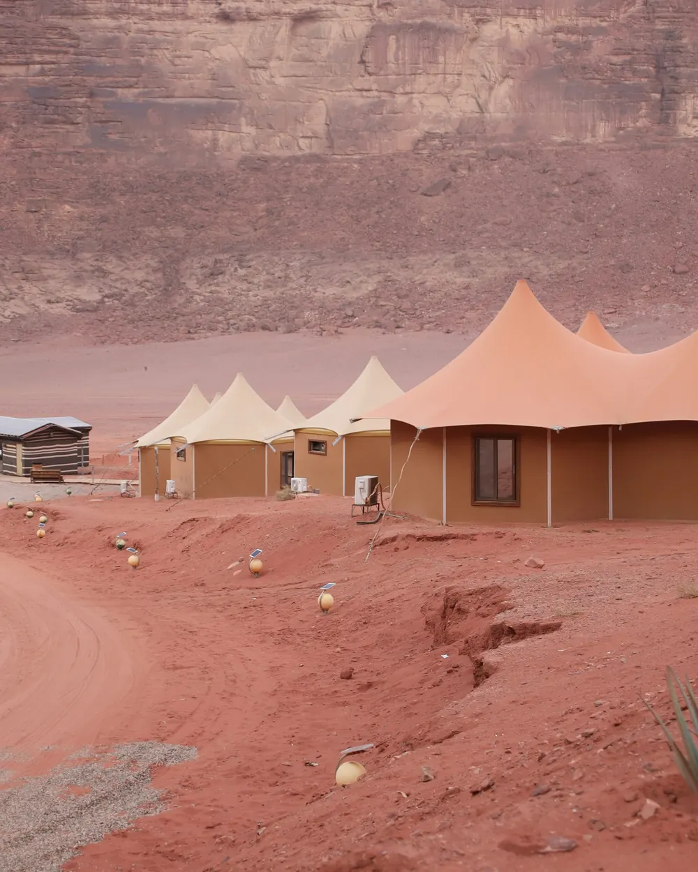 Family tents with peaked roofs below a sandstone mountain