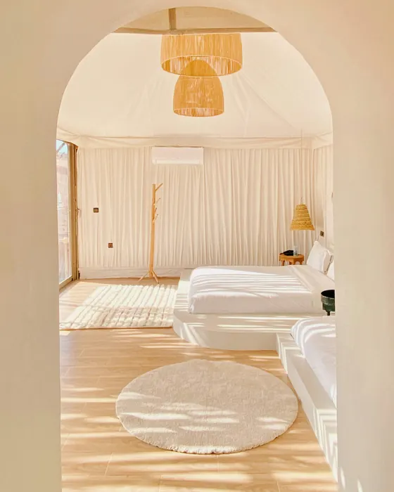 A bright room with two white beds and a round rug